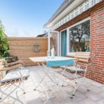 Terrace with table, chairs, and anchor on wooden wall.