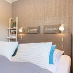 Bedroom with bed, pillows, and nightstands. Wall with textile covering and bookshelves.