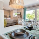 Dining room with table setting and garden view. Bedroom with bed in background.