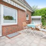 Terrace with table, chairs, and sunshade in front of red brick house.