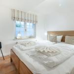 Bedroom with double bed, wooden frame, window, and anchor decoration.