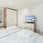 Bedroom with bed, wardrobe, TV, and mirror.