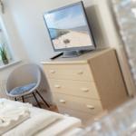 Bedroom with bed, desk, and television.