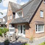 Red brick house with terrace and garden. White windows and dormers.