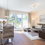 Living and dining area with sofa, dining table, and garden view.