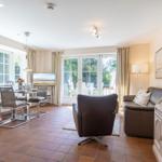 Living and dining area with terrace door, sofa, armchair, and dining table.