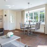 Living and dining area with terracotta floor, glass furniture, and TV.