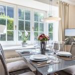 Dining table with chairs, flowers, and garden view through windows