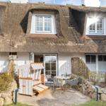 House with thatched roof, terrace with lounge chair and table