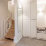 Entrance area with stairs, mirror, and seat with cushion.