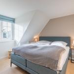 Bedroom with dormer window, bed, and bedside table.