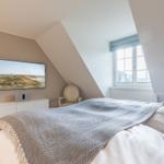 Bedroom with sloped ceiling, bed, window, and TV mounted on the wall.