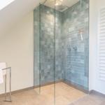 Shower with glass enclosure and colored tiles, towel rack and heater
