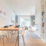 Dining area with table and chairs, view into living room with sofa and bookcase.