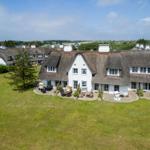 House with thatched roof and large garden. Outdoor seating area.