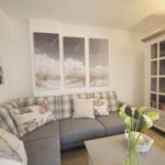 Living room with sofa, cushions, and glass cabinet. Wall art shows beach motif.