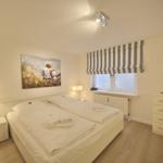 Bedroom with double bed, window, TV, and nightstand.