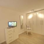 Bedroom with wardrobe, chair, and TV on cabinet.