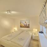 Bedroom with double bed, two nightstands, and wall art.