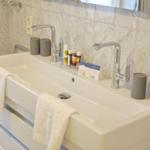 Bathroom with sink, two faucets, and gray containers.