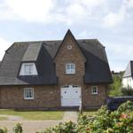 House with brick facade, dark roof, and white door. Number 14. Lawns and paved paths.