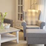 Living room with armchair, sofa, table, and curtains.