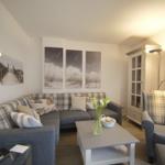 Living room with sofa, armchair, and table. Pictures hang on the walls.