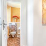 Bathroom with toilet, mosaic wall, and flowers