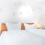 Bedroom with white bedding, wooden headboard, and bird wall decor.