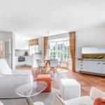 Living room with dining area and kitchen. Terracotta floor and large windows.