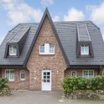 Haus mit Ziegelfassade und schwarzem Satteldach mit Dachfenstern.