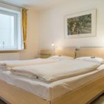 Schlafzimmer mit Doppelbett, Fenster und Nachttischen.
