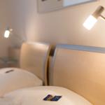 Zwei Betten mit Holz-Kopfteil und Nachttisch mit Lampe.