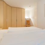 Schlafzimmer mit Bett, Kleiderschrank und Stuhl.
