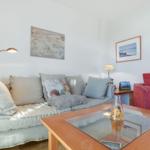 Wohnzimmer mit Sofa, rotem Sessel und Glas-Tisch