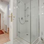 Badezimmer mit Dusche, Toilette und Blick in den Flur.