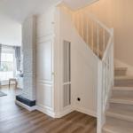 Treppenhaus mit weißer Treppe und integriertem Schrank neben Steinwand