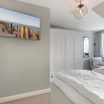 Schlafzimmer mit Bett, Kleiderschrank und TV an der Wand.