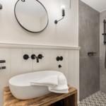 Bad mit Dusche, Waschbecken auf Holz und runden Spiegel.
