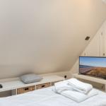 Schlafzimmer mit Bett, Fernseher und Kleiderschrank unter Dachschrägen.