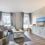 Wohnzimmer mit Sofa, Couchtisch und Fernseher an weißem Schrank