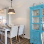 Essbereich mit Tisch, Stühlen und blauem Schrank. Küche im Hintergrund.