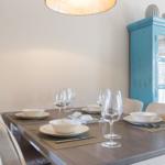 Esstisch mit Stühlen, Geschirr und blauem Schrank.