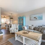Wohnzimmer mit Kamin, Sofa und Küchenbereich im Hintergrund.