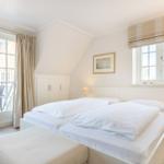 Schlafzimmer mit Doppelbett, Fenster und Balkonzugang.