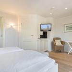 Schlafzimmer mit Bett, Fernseher und zwei Stühlen.