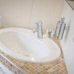 Waschbecken mit Chromhahn und Seifenspender auf Mosaik-Arbeitsplatte