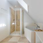 Badezimmer mit Dusche, Badewanne und Heizkörper unter Dachschräge