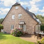 Haus mit Steinmauer, Terrasse und Blumenbeete im Garten