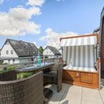 Terrasse mit Liege, Tisch und Stühlen. Blick auf Dächer und Himmel.